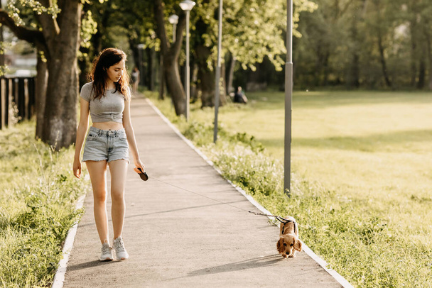 mooie jonge vrouw met haar cocker spaniel puppy tijd doorbrengen samen in park - Foto, afbeelding