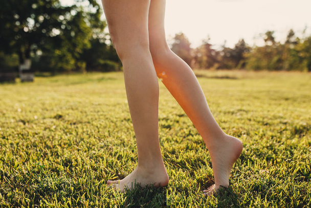 recortado disparo de descalza mujer caminando sobre verde hierba - Foto, imagen