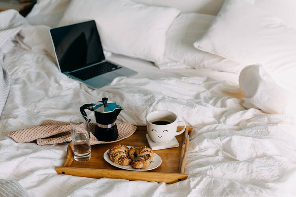 primer plano de sabrosos croissants y taza de café en bandeja de madera en la cama - Foto, imagen
