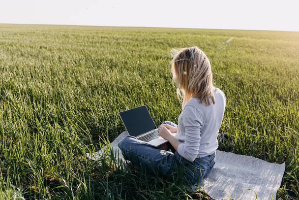 hermosa mujer joven que trabaja con el ordenador portátil en el campo verde - Foto, Imagen