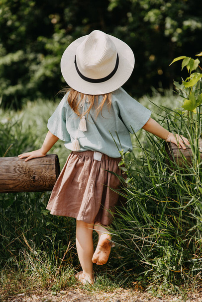rear view of stylish little girl in dress spending time outdoors - Photo, image