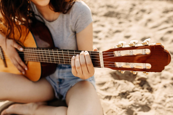砂浜でアコースティックギターを持った女性が切り取られ - 写真・画像