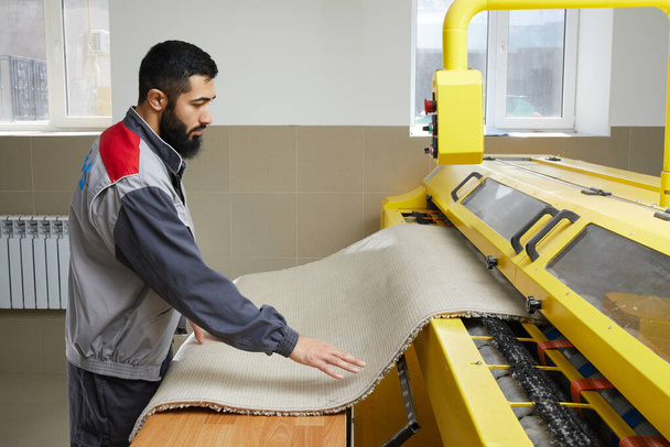 Человек работает ковер автоматическая стиральная машина в профессиональной прачечной - Фото, изображение