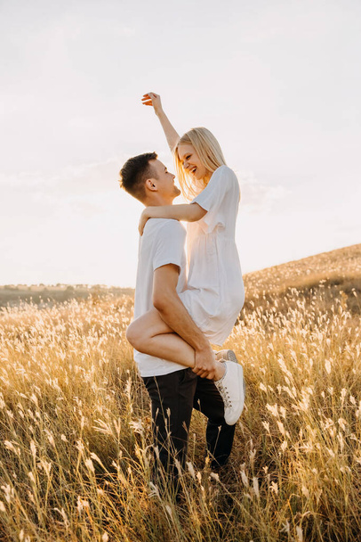 beautiful young couple embracing on meadow during sunset - Valokuva, kuva