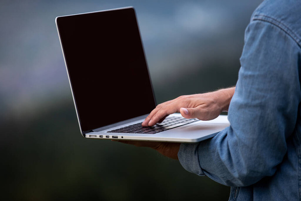 Человек работает на открытом воздухе с ноутбуком в горах. Концепция удаленной работы или образ жизни фрилансера. Широкополосный охват сотовой сети. интернет 5G - Фото, изображение