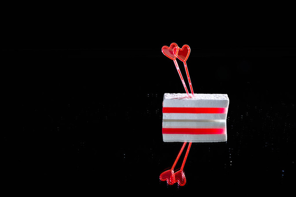 Witte suikerspin met laag rode marmelade en twee hartvormige spiesjes op een zwarte achtergrond met spiegelreflectie met kopieerruimte. Het Wit-Russische volk is tegen politiek geweld. Toetje. - Foto, afbeelding