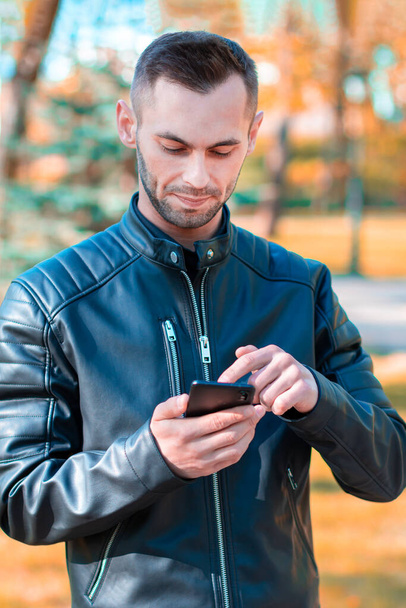 Handsome Guy Using Smartphone at Autumn Park - Φωτογραφία, εικόνα