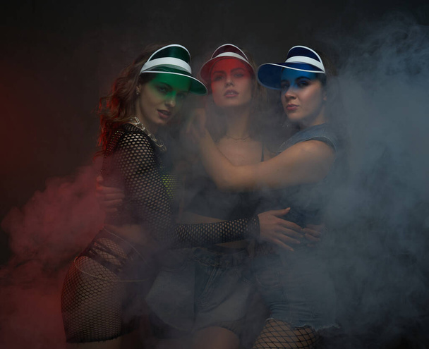 Glamour girls in sexy clothing with caps posing smokey background - Photo, Image