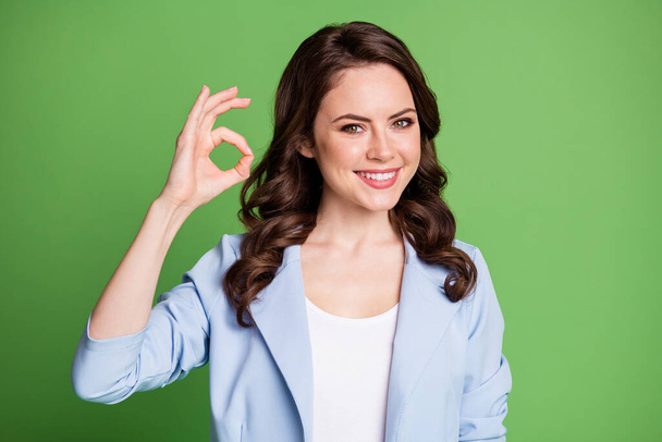 Photo of charming lady curly hairdo hand demonstrate okey wear blue jacket isolated green color background - Fotografie, Obrázek