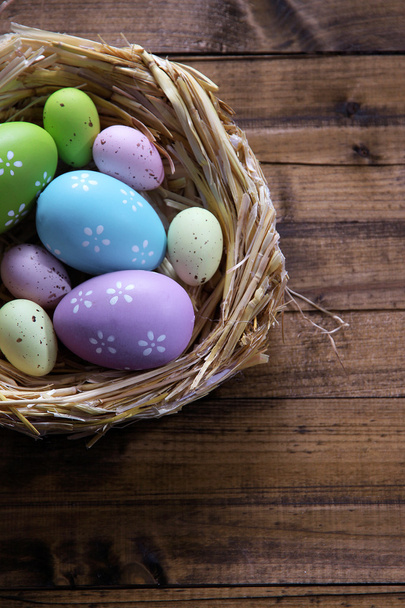Easter eggs in nest on color wooden background - 写真・画像