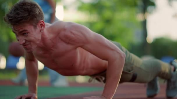 Close-up emotionele gespierde sportman doet push-ups in de sport speeltuin buiten. - Video