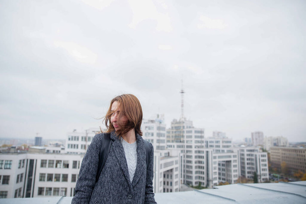 Young woman on the roof of a building with a city in the fog behind - Foto, Imagem