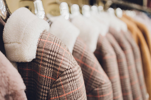 Kabátok és zakók a vállfán a boltban. Felsőruházat értékesítése. - Fotó, kép