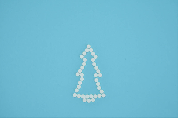Luova joulukuusi, joka on tehty pillereistä sinisellä taustalla. Joulukortteja. Hyvää joulua. Kopioi tilaa. valikoiva kohdentaminen - Valokuva, kuva