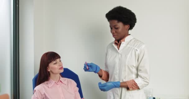 Una giovane infermiera fa un esame del sangue da un paziente. Impiegata dell'ospedale al primo piano della sala laboratorio. Campionamento di sangue per gli anticorpi del virus della corona da parte dell'infermiere di medicina all'interno. Test di microbiologia scientifica - Filmati, video