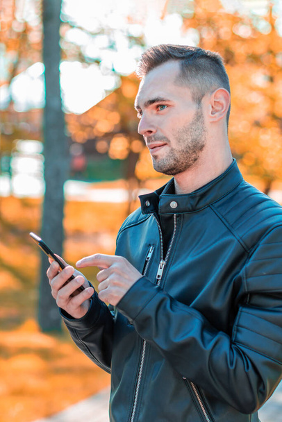 Handsome Guy Using Smartphone at Autumn Park - Foto, immagini