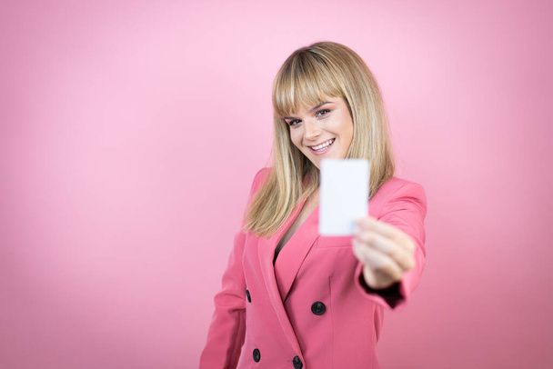 若いですcaucasian女性上の隔離されたピンクの背景笑顔とホワイトカード - 写真・画像