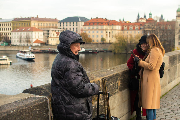 チェコ共和国プラハ。01-11-2020 。観光客は歴史的な町のチャールズ橋を歩いています。橋の上からホームレスが始まる. - 写真・画像