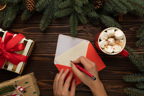 Un uomo scrive una lettera a Babbo Natale con gli auguri di Natale. Tavolo decorato con arredamento di Capodanno. - Foto, immagini