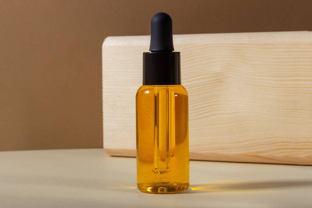 A glass cosmetic bottle with a dropper on a beige background in bright sunlight. The concept of natural cosmetics, natural essential oil. - Valokuva, kuva