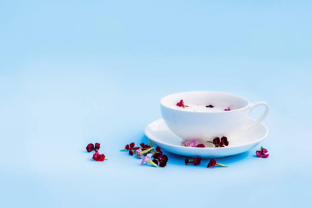 White Cup with vegan milk and flowers on a blue background. Concept of vegetarian drinks and food, herbal teas, beauty and health, Spa. - Fotoğraf, Görsel