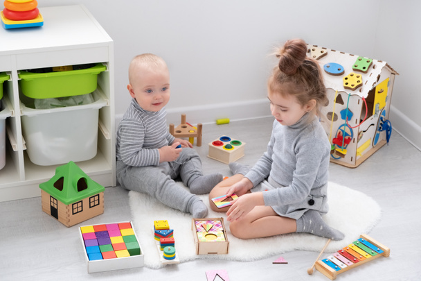 A kisfiú fából készült játékokkal játszik a nővérével. kisgyermekek fejlődése - Fotó, kép
