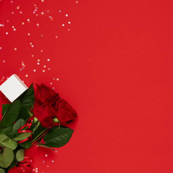 San Valentino modello piatto lay. Fiori rose con scatola regalo su sfondo rosso con posto per il testo - Foto, immagini