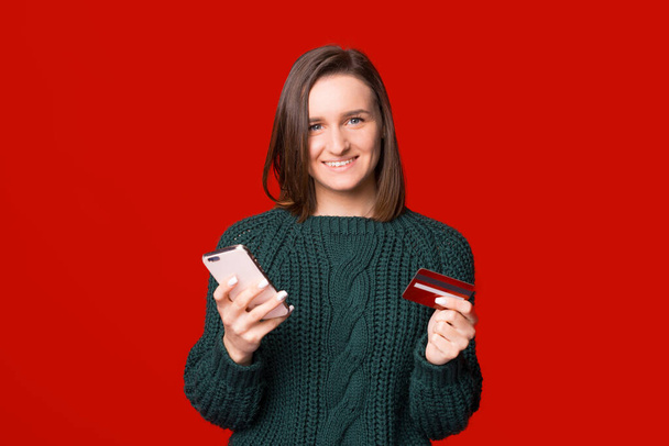 Junge hübsche Frau nutzt Handy und Karte für mobiles Banking oder Online-Shopping. - Foto, Bild