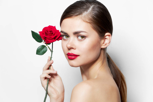 Η κυρία με το τριαντάφυλλο κρατά ένα λουλούδι κοντά στο πρόσωπο κόκκινα χείλη κόκκινα χείλη  - Φωτογραφία, εικόνα