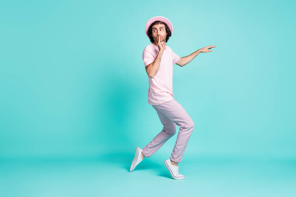 Full length profile photo of funky guy slow hush steps wear spectacles cap t-shirt trousers sneakers isolated on teal color background - 写真・画像