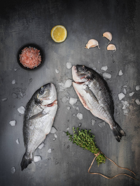 Tengeri keszeg - dorádó tengeri hal, kakukkfű, citrom, fokhagyma és himalájai só sötét szüreti alapon. Mediterrán konyha. Felülnézet fénymásoló felülettel. - Fotó, kép