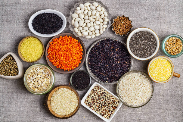 Food background of various cereals and grains in plates on a canvas, top view - Photo, Image