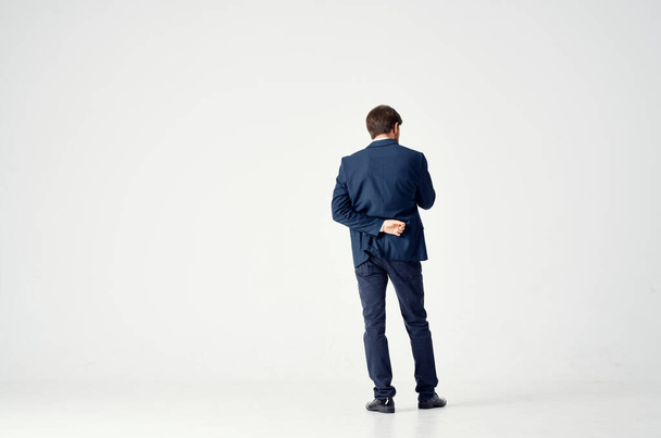 Rückansicht eines Mannes im Anzug auf hellem Hintergrund, der mit seinen Händen in vollem Wuchs gestikuliert - Foto, Bild