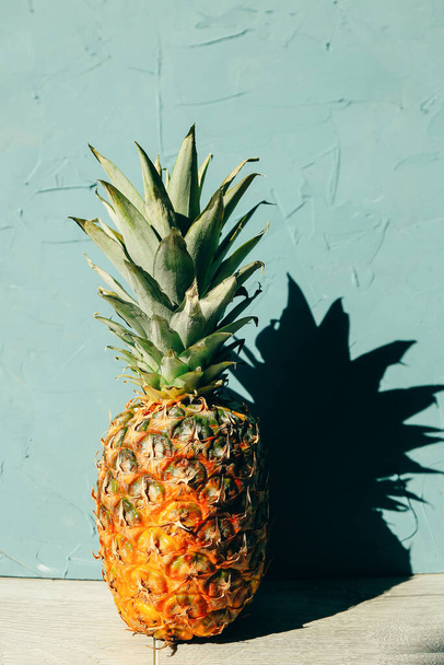 Large ripe pineapple with a shadow, copy space over wooden background in tropical theme - Φωτογραφία, εικόνα