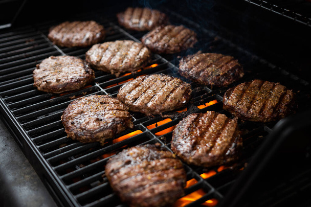 Hamburgers and hot dogs cook on flame charred backyard grill - Photo, Image