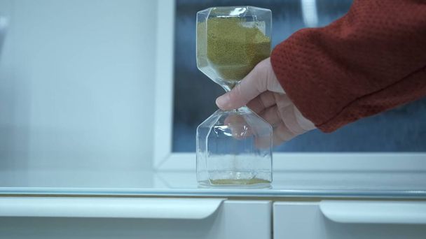 Mulher mão vira uma ampulheta de vidro - Foto, Imagem
