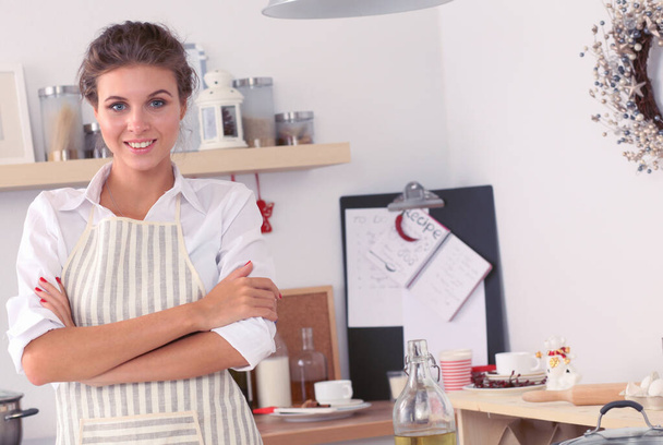 Smiling young woman in the kitchen, isolated on christmas background - Photo, Image