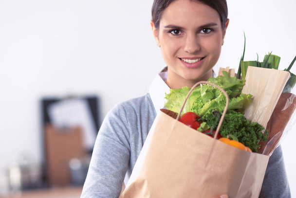 Young woman holding grocery shopping bag with vegetables Standing in the kitchen. - Foto, imagen