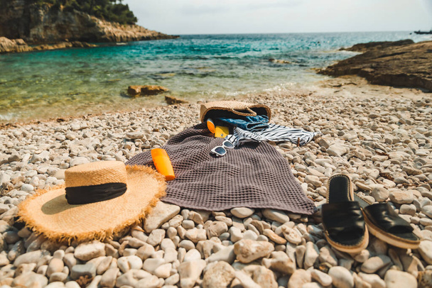 Plaj malzemesi battaniyesi, güneş koruması, krem hasır şapka ve düz çanta. - Fotoğraf, Görsel