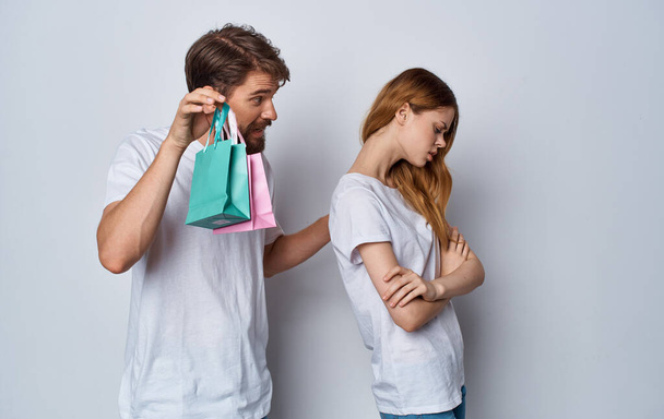 offended woman turned away from a man with gift bags on a light background - Photo, Image