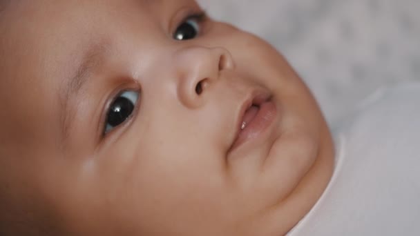 Glückliches neugeborenes Baby mit dunkler Haut, das auf der Decke lächelt. Nahaufnahme - Filmmaterial, Video