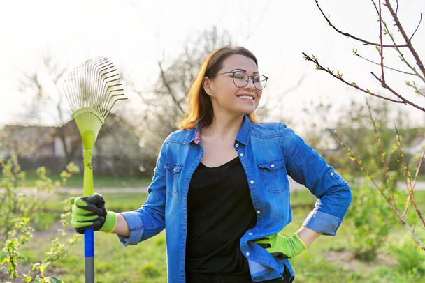 Spring gardening, portrait of mature smiling woman gardener with rake - Foto, imagen