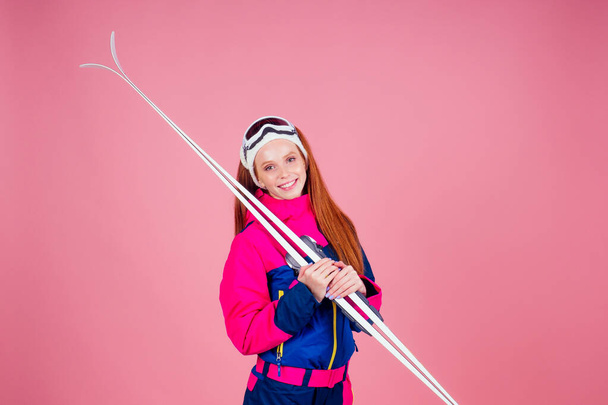 redhaired ginger young woman with skis posing in studio on pink background - Photo, image
