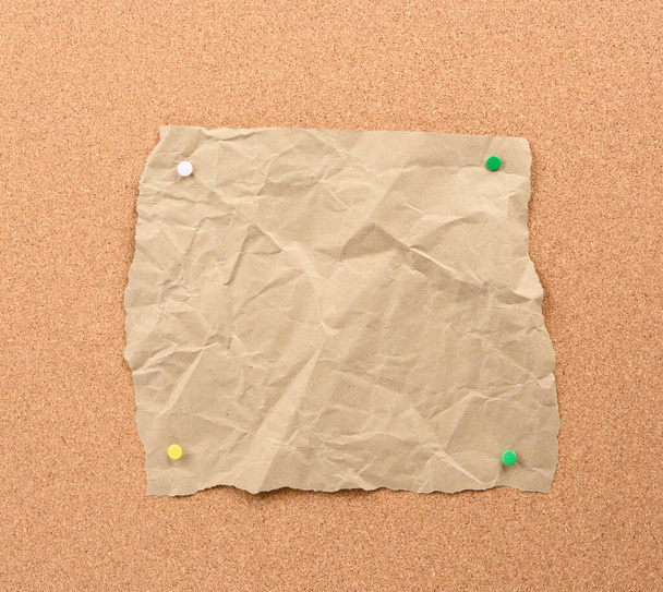 茶色の板に鉄のボタンで固定された引裂かれた紙コピースペース - 写真・画像