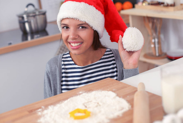 Woman in santa hat making christmas cookies in the kitchen - Foto, imagen