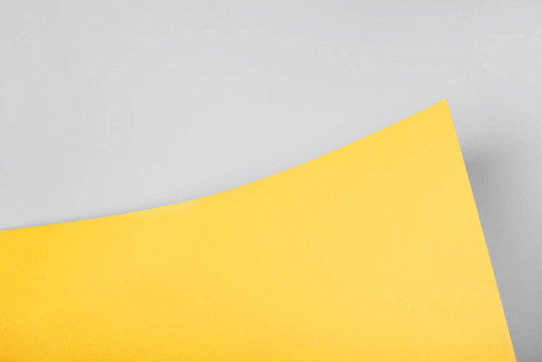 Gelber und grauer abstrakter Papierhintergrund von einem gebogenen Blatt. Leerzeichen für Website, Werbung, Präsentation - Foto, Bild