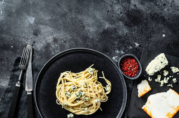 Spaghetti pasta with blue Gorgonzola cheese sauce. Black background. Top view. Copy space. - Photo, image