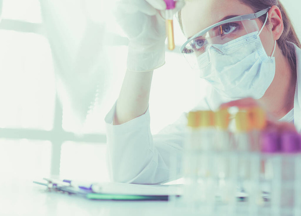Portrait of pretty female laboratory assistant analyzing a blood sample at hospital - Фото, зображення