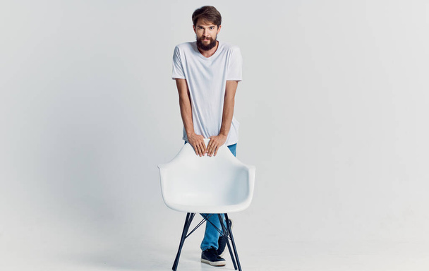 bearded man in white t-shirt near chair lifestyle isolated background - Zdjęcie, obraz
