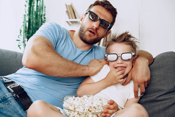 Father and son watching movies at home in 3d glasses and eating popcorn - Photo, image